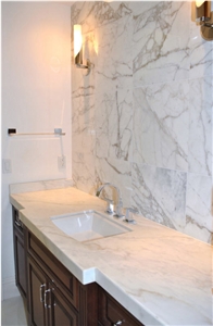 Traditional Bathroom Featuring White Marble Vanity and Calacatta Gold Marble Tile Wall